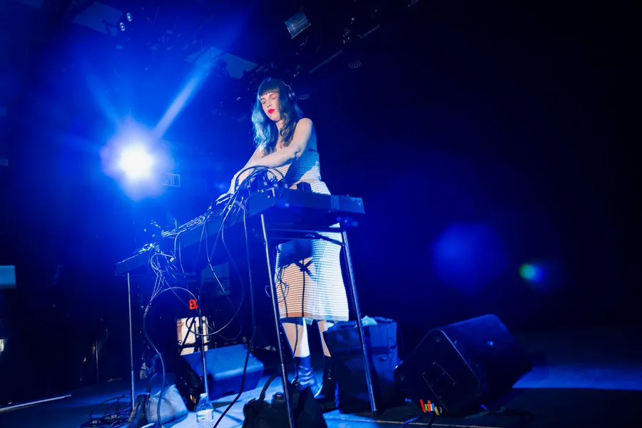 Performer at a keyboard rig under a blue spotlight